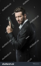 stock-photo-confident-undercover-agent-with-a-gun-against-dark-background-246820759